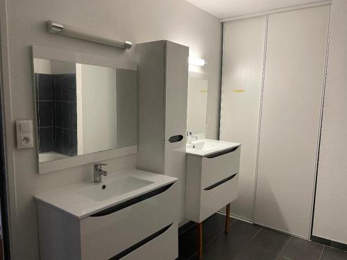 une salle de bain blanche avec un lavabo et un miroir dans l'établissement IRIS 82, à Lorette