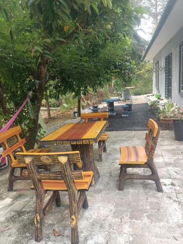 a group of wooden tables and chairs under a tree at Cp homestay in Batu Kurau