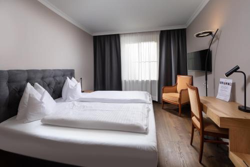 a hotel room with two beds and a desk at Hotel Goldene Sonne in Landshut