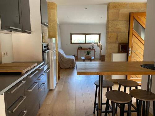 - une cuisine avec une table et quelques tabourets dans une pièce dans l'établissement Le Shala - 55m² + Jardin, à Tabanac