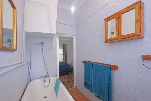 ein Badezimmer mit einer weißen Badewanne und einem blauen Handtuch in der Unterkunft Sun Garden Cottage in Johannesburg