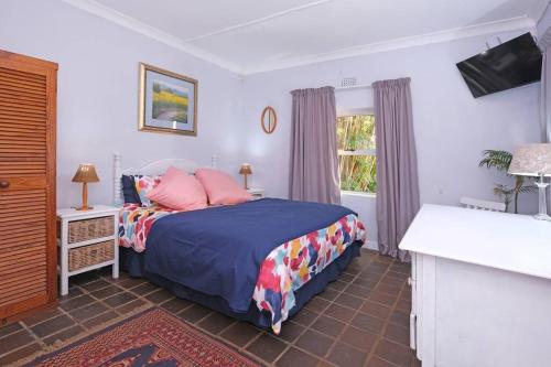 Schlafzimmer mit einem Bett mit rosa Kissen und einem Fenster in der Unterkunft Sun Garden Cottage in Johannesburg