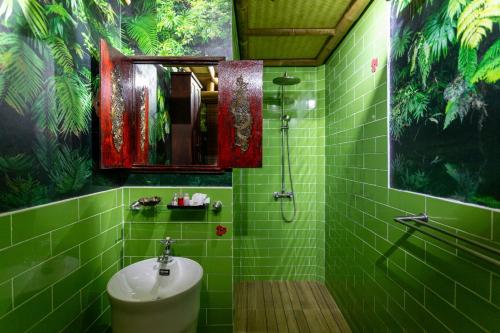 un bagno piastrellato verde con lavandino e doccia di The Parrot Inn Kanchanaburi a Kanchanaburi