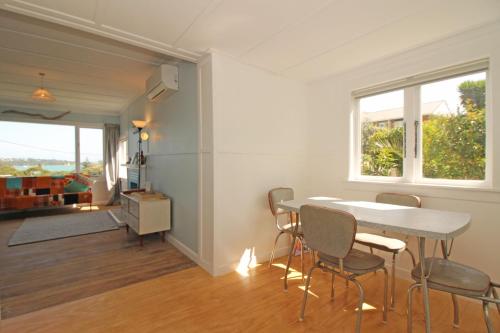 a dining room with a table and chairs and a window at Classic bach near the beach in Oneroa