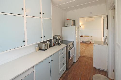 a kitchen with white cabinets and a white refrigerator at Classic bach near the beach in Oneroa