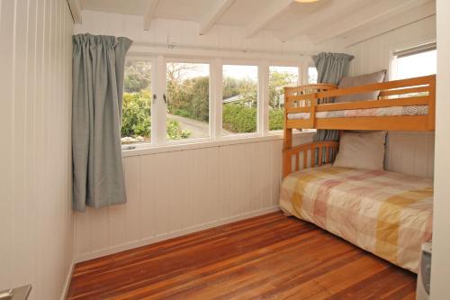 1 dormitorio con litera y 2 ventanas en Classic bach near the beach, en Oneroa