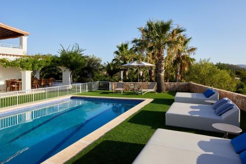 una piscina con sedie a sdraio e una casa di Villa Can Joan I - Fantastic Sunset Views and Family Friendly - a San Antonio