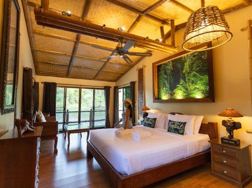 um quarto com uma cama grande num quarto em The Parrot Inn Kanchanaburi em Kanchanaburi