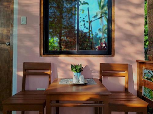 a wooden table with two chairs and a window at NoBi's Inn, Port Barton in San Vicente