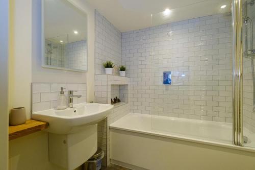 Un baño blanco con lavabo y bañera. en Drake House, en Aldeburgh