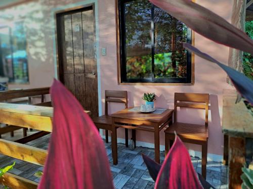 a patio with a wooden table and chairs and a table and chairs at NoBi's Inn, Port Barton in San Vicente