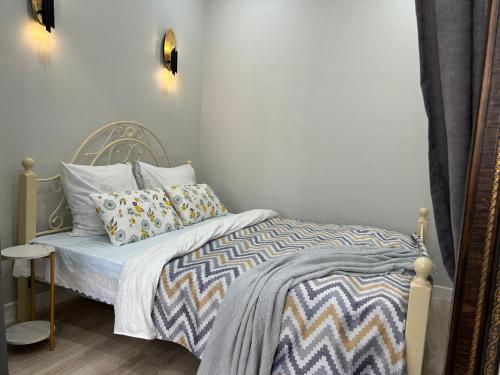 ein kleines Schlafzimmer mit einem Bett mit einer Bettdecke und Kissen in der Unterkunft Квартира в Актау 362 in Aqtau