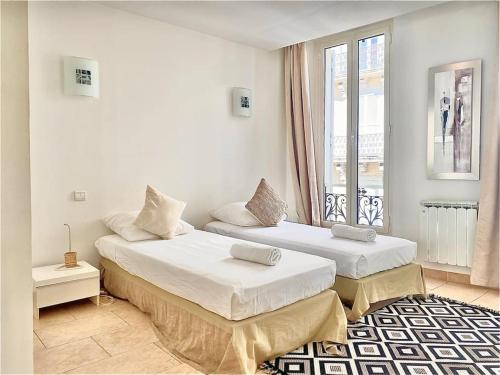 deux lits dans une chambre blanche avec une fenêtre dans l'établissement Appartement Cannes 3 chambres - 8B2, à Cannes