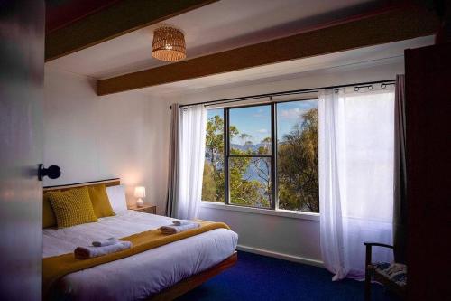 a bedroom with a bed and a large window at Killora Coastal Shack in Killora