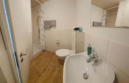 a white bathroom with a sink and a toilet at MBar in Altnau