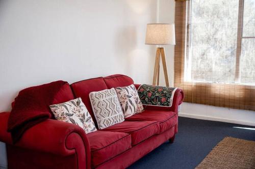 a red couch with pillows on it in a living room at Killora Coastal Shack in Killora