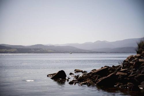 a large body of water with rocks in the water at Killora Coastal Shack in Killora