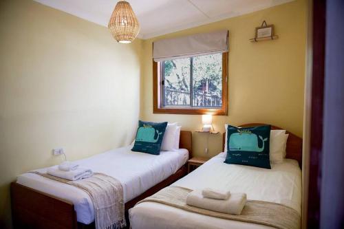 two twin beds in a room with a window at Killora Coastal Shack in Killora