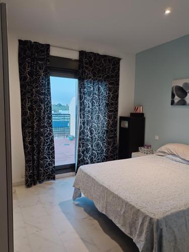 een slaapkamer met een bed en een raam met uitzicht bij Ático Mirabal in Mairena del Aljarafe