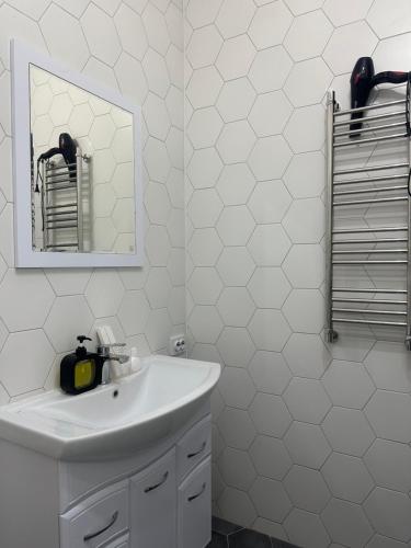 La salle de bains blanche est pourvue d'un lavabo et d'un miroir. dans l'établissement park home uralsk, à Uralsk