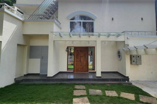 a house with a brown door and a grass yard at SS Lumina Villa in Bengaluru