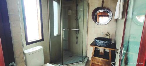 a bathroom with a shower and a toilet and a mirror at Longji Holiday Hotel in Longsheng