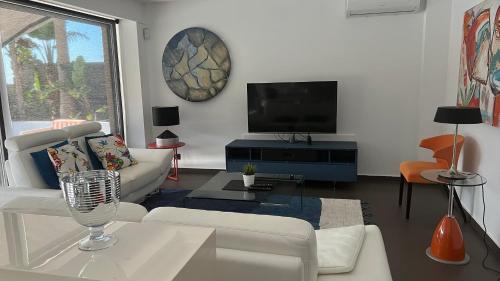 a living room with a white couch and a tv at Villa de luxe vue mer et piscine privée casa de Palma à Torrox Costa in Torrox Costa