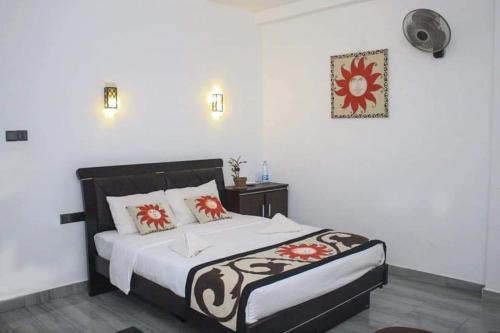 a bedroom with a bed with red and white pillows at Hotel Sojan in Veyangoda