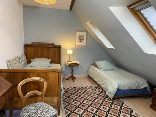 a attic room with two beds and a chair at Chez Rosa in Haguenau