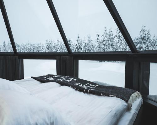 uma cama num quarto com uma grande janela em Northern Lights Village Pyhä em Pyhätunturi