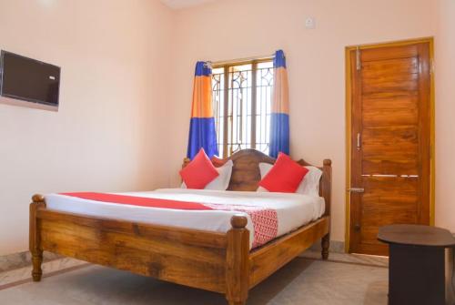 een slaapkamer met een houten bed met rode en blauwe kussens bij Goroomgo Caroline Homestay Bhubaneswar in Bhubaneshwar
