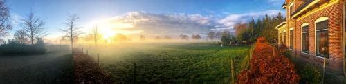 a misty field with the sun in the sky at B&B Zandhuizen in Zandhuizen