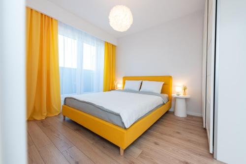 Un dormitorio con una cama amarilla y una ventana en ART Apartment II, en Târgu Mureș