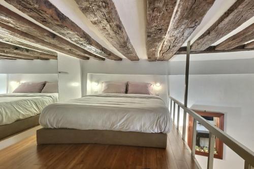 a bedroom with two beds and a wooden ceiling at Le Saint Claude in Paris