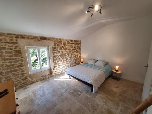 a bedroom with a bed and a brick wall at Chez Véro chambres d'hôtes & Maison en pierre contemporaine in Suze-la-Rousse