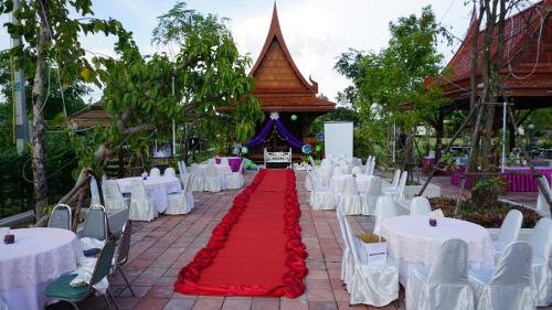 a banquet hall with white tables and a red carpet at Sripiamsuk Resort Bangkok in Pathum Thani