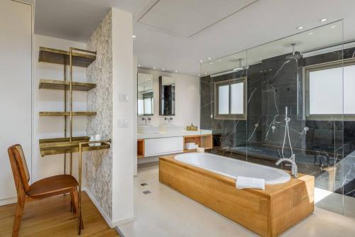 a large bathroom with a tub and a chair at #Breathtaking 4BR/3BA Duplex Seafront in Tel Aviv