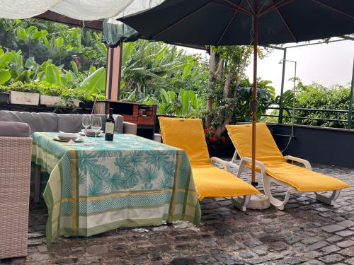 a table and chairs with an umbrella on a patio at Villa Formosa in Funchal