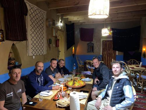 a group of men sitting at a table eating pizza at Auberge & Restaurant Agoudal in Agoudal