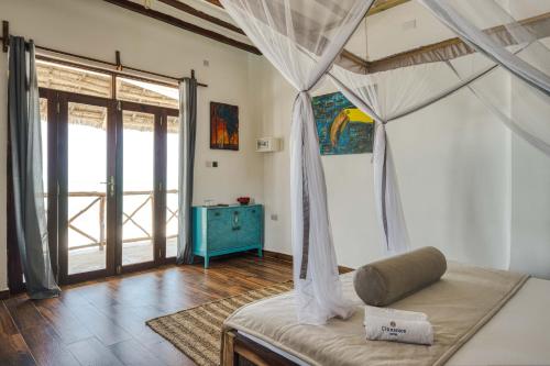 a bedroom with a canopy bed and a blue dresser at Cinnamon Hotel in Jambiani
