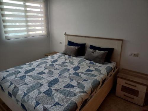 a bedroom with a bed with a blue comforter and a window at Apartamento Playa de Xilxes. in Moncófar