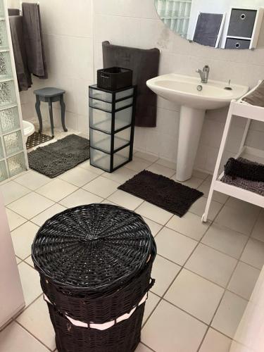 a bathroom with a sink and a toilet and a basket at Kaz Zézère ô coeur du Bras Creux Tampon in Le Tampon