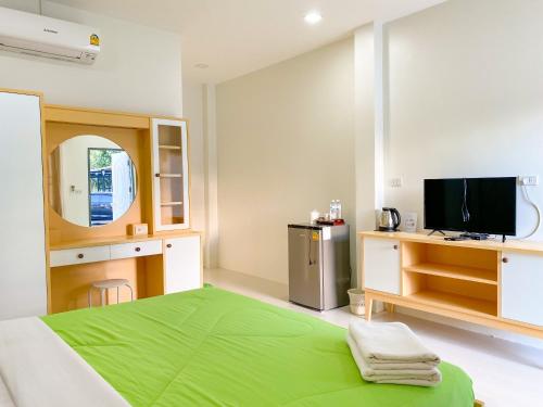 1 dormitorio con 1 cama verde y TV en บ้านพักสิริ มุกดาหาร (Baan Siri Mukdahan) en Ban Muang Ba