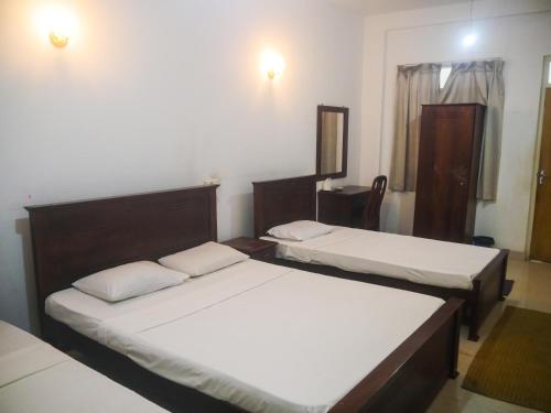 a bedroom with two beds and a mirror at Visaka Hotel - Kataragama in Kataragama