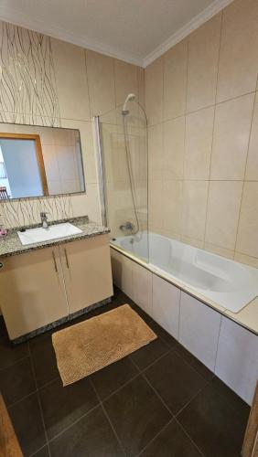 a bathroom with a sink and a bath tub at Ocean Breeze Apartment in São Vicente