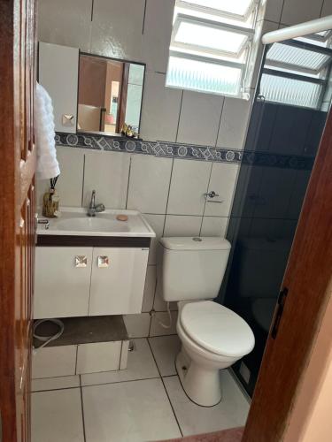 a bathroom with a white toilet and a sink at Kitnet ao lado do centro in Itabira