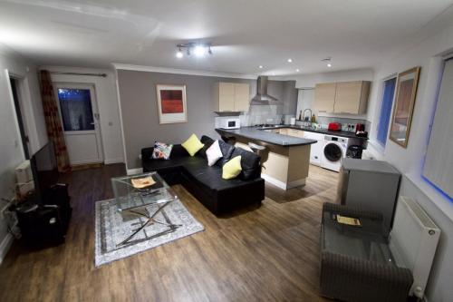 a living room with a black couch and a kitchen at Mill Lane Refurbished 2 Bedroom Apartment in Newbury