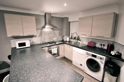 a kitchen with a stove and a washer and dryer at Mill Lane Refurbished 2 Bedroom Apartment in Newbury