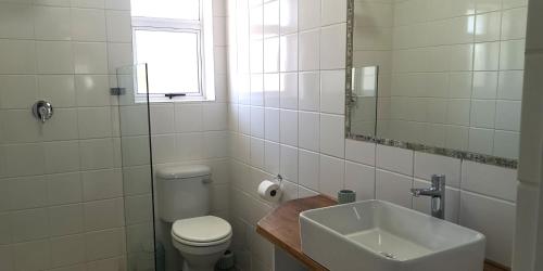 a bathroom with a sink and a toilet and a mirror at Secrets 2 at Waterkant 7 in Jeffreys Bay