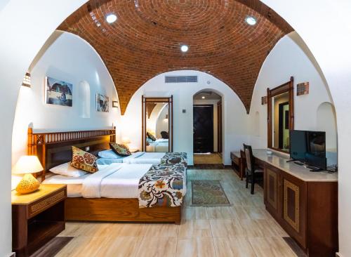a bedroom with a bed and a desk and a tv at Beach safari nubian resort in Marsa Alam City